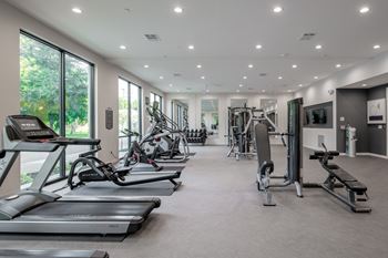 A spacious gym with treadmills, exercise bikes, and weight machines.
